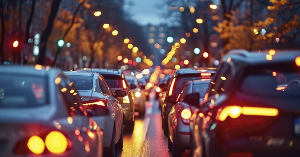 Rush-hour city street with bumper-to-bumper cars and warm bokeh lights at dusk